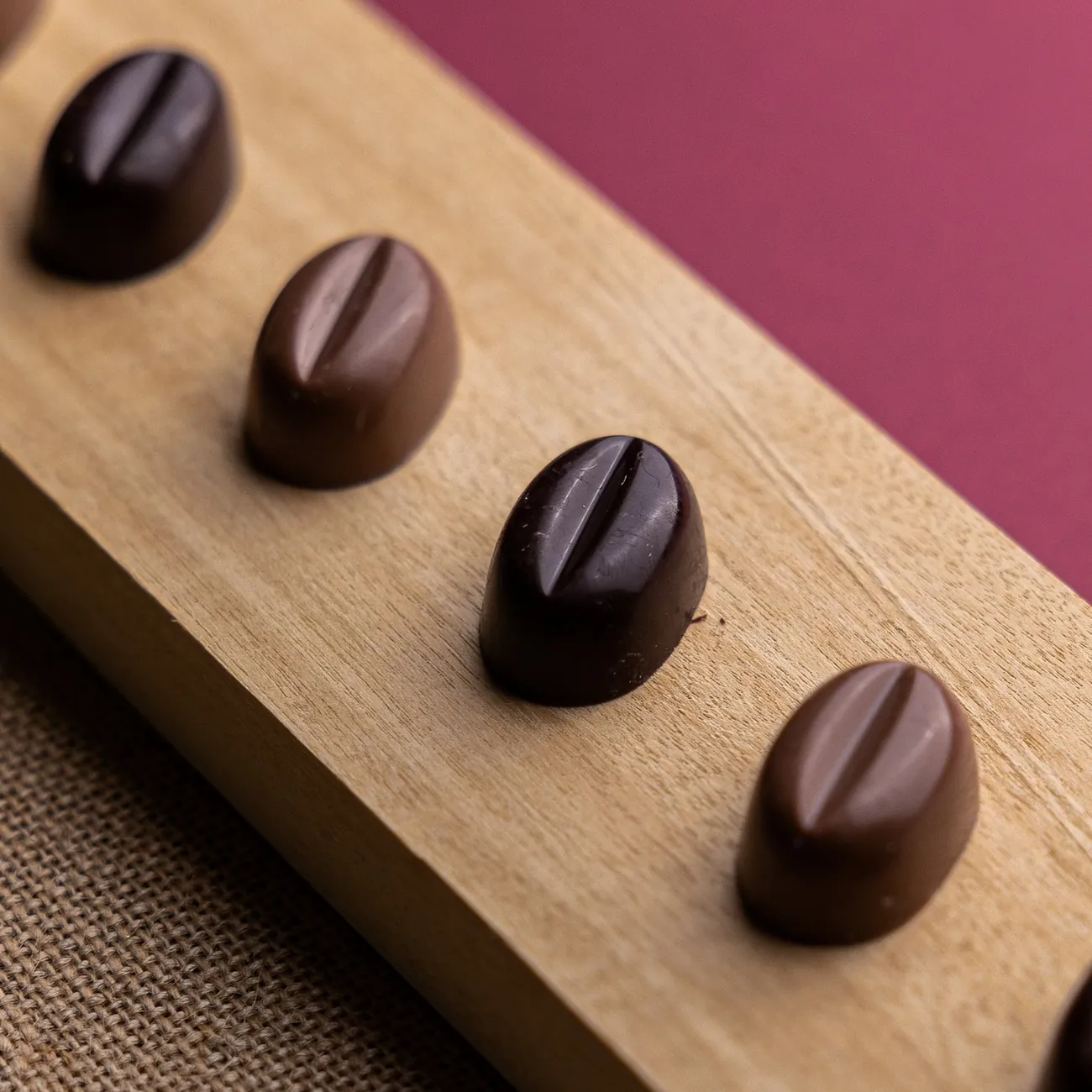 Cioccolatini al latte e fondenti in fila su un tagliere di legno
