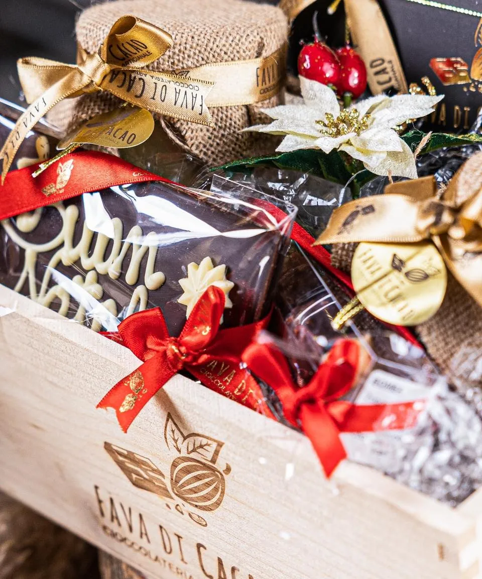 Cassetta regalo di Natale col logo, piena di cioccolato, nastri rossi e liquore