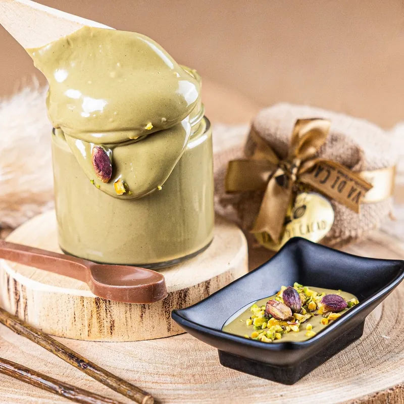 Crema spalmabile al pistacchio che cola dal cucchiaio nel vasetto
