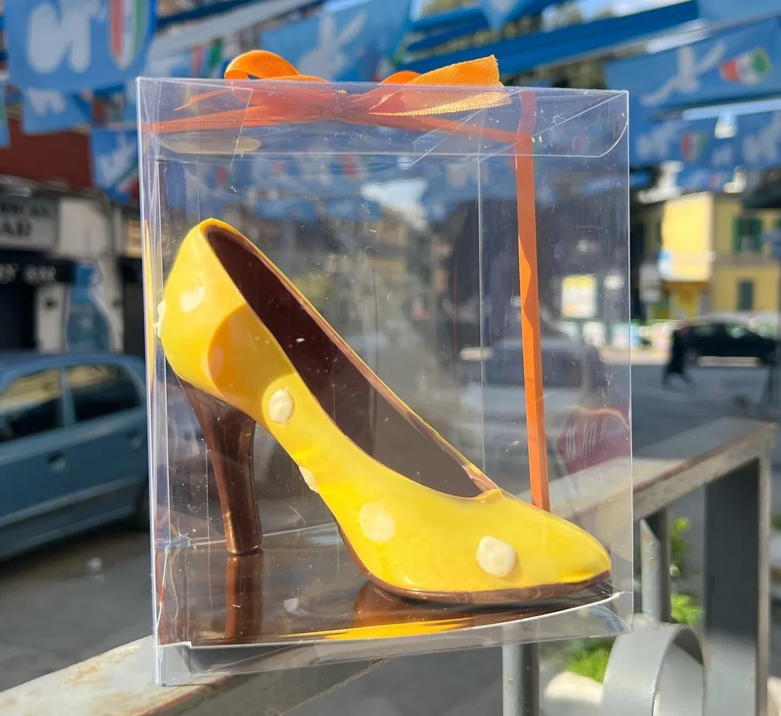 Scarpa col tacco di cioccolato dipinta di giallo, in una scatola trasparente